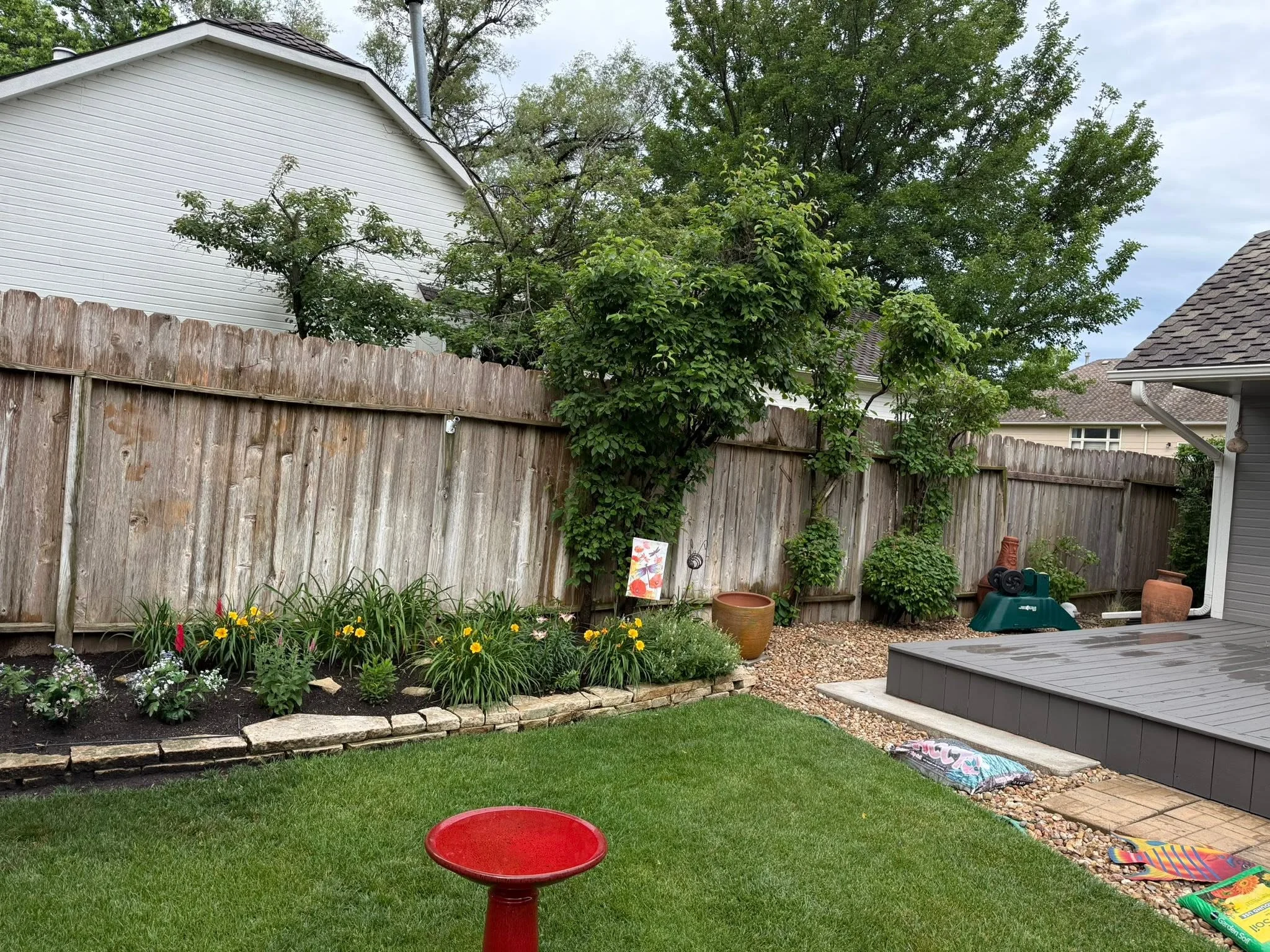 Wood privacy fence with stone-edged flower beds and gravel landscaping in residential backyard