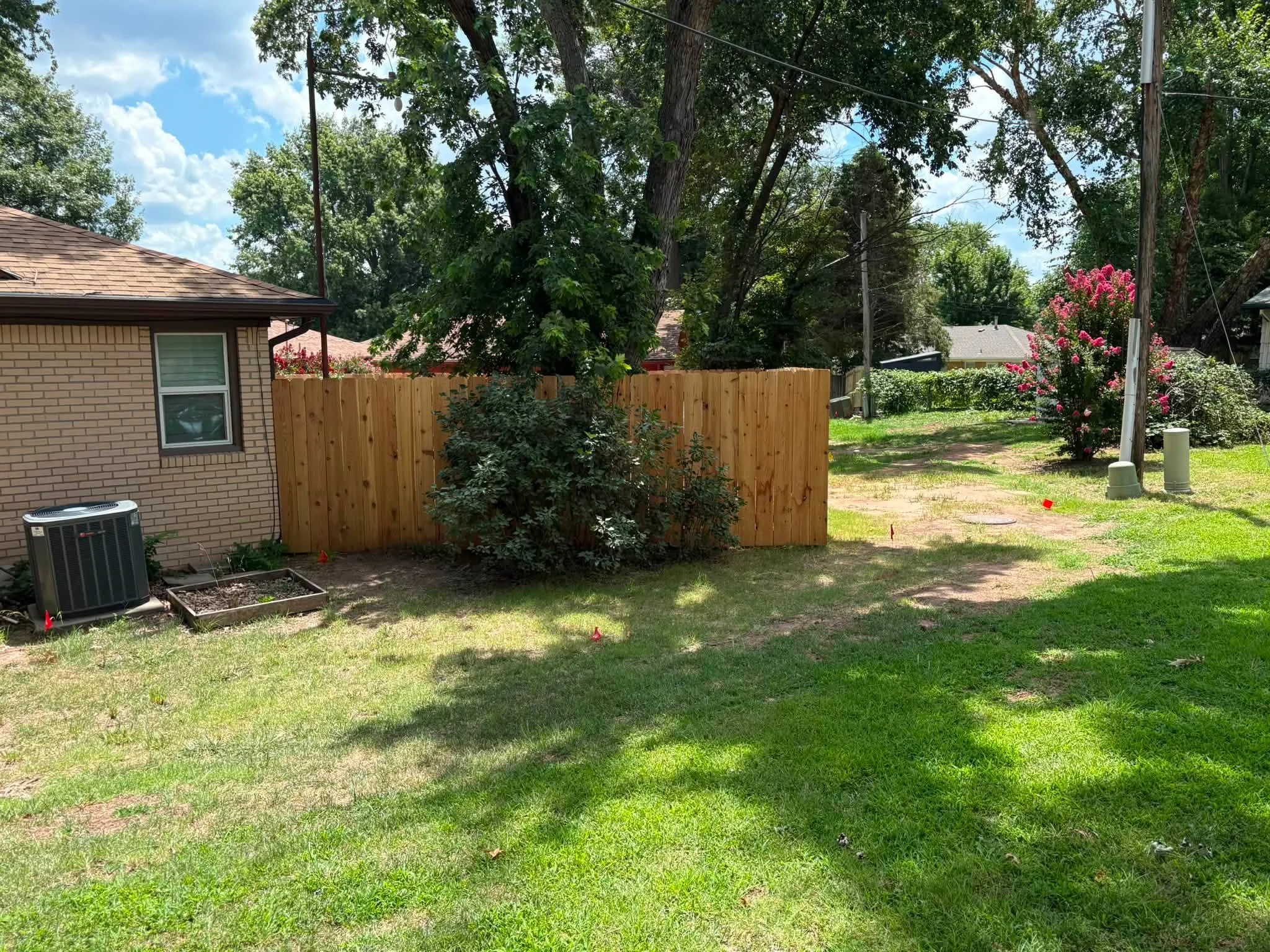 Cedar wood privacy fence with vertical boards installed along residential backyard property line