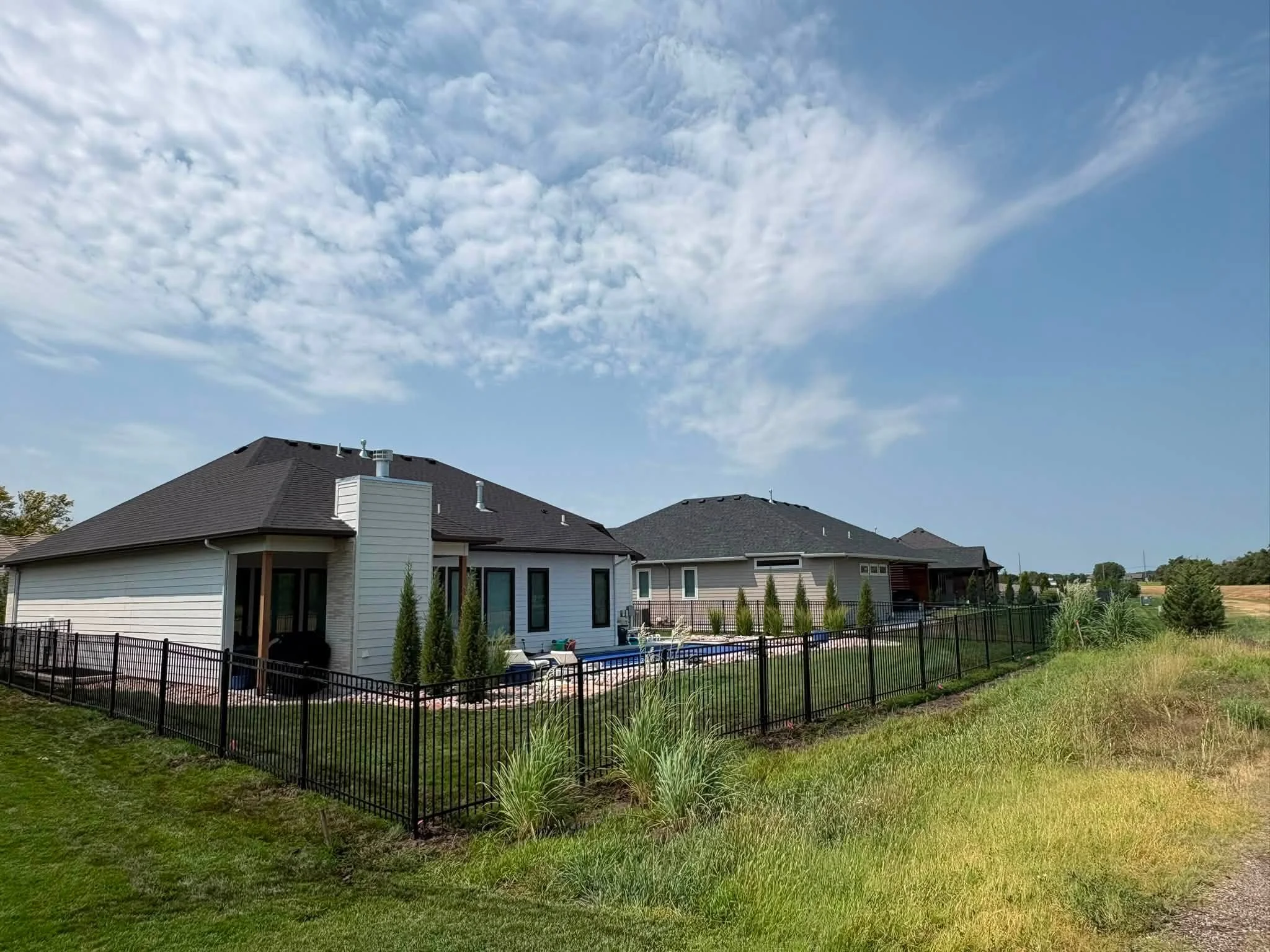 Black aluminum picket fence around residential pool area with modern home