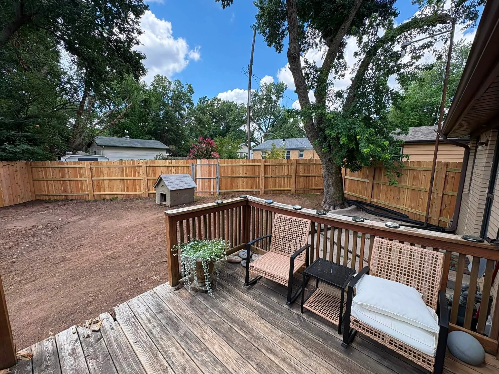 Cedar wood privacy fence with vertical boards surrounding backyard deck and landscaping