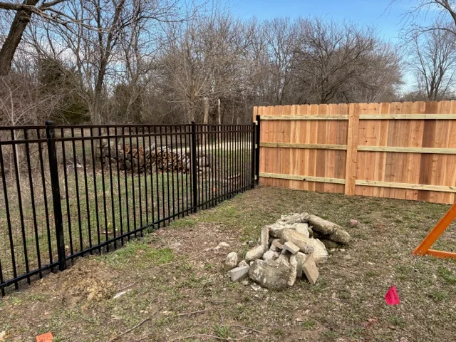 Black aluminum ornamental fence and cedar wood privacy fence with gate installed in residential yard