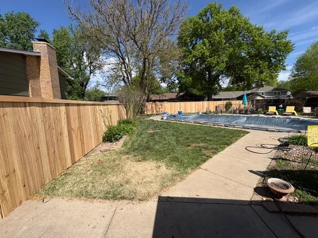 Cedar wood privacy fence with vertical boards installed in residential backyard