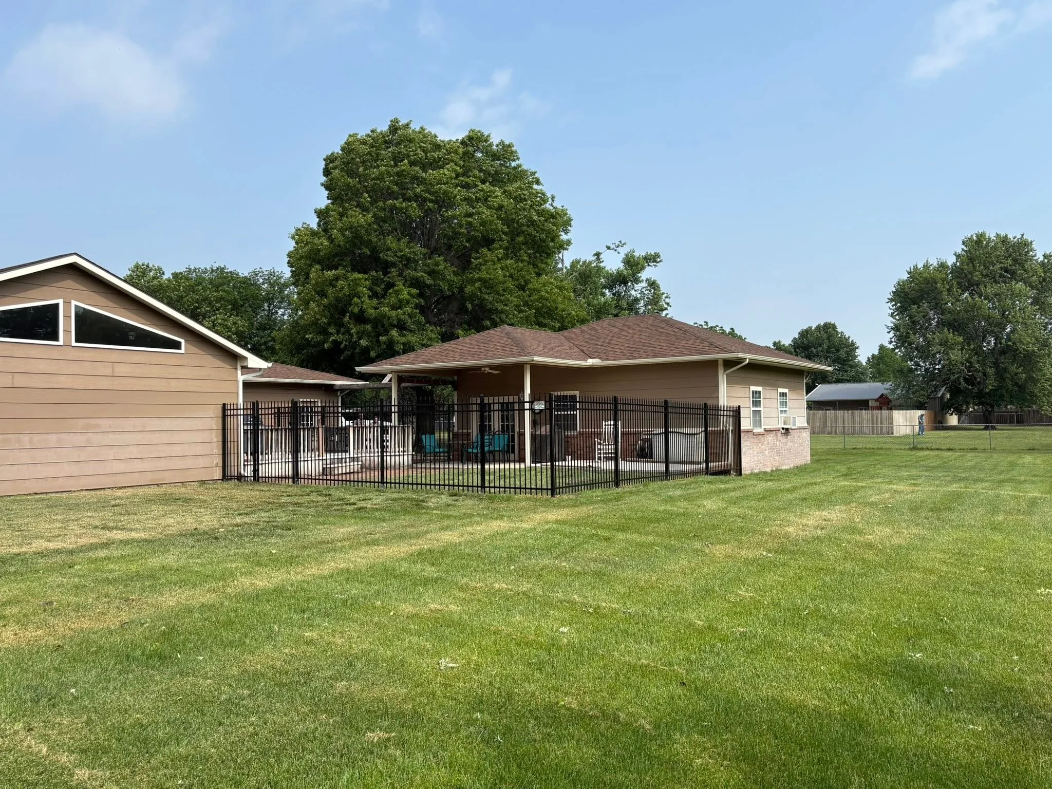 Black aluminum ornamental fence enclosing residential patio with vertical pickets and concrete base