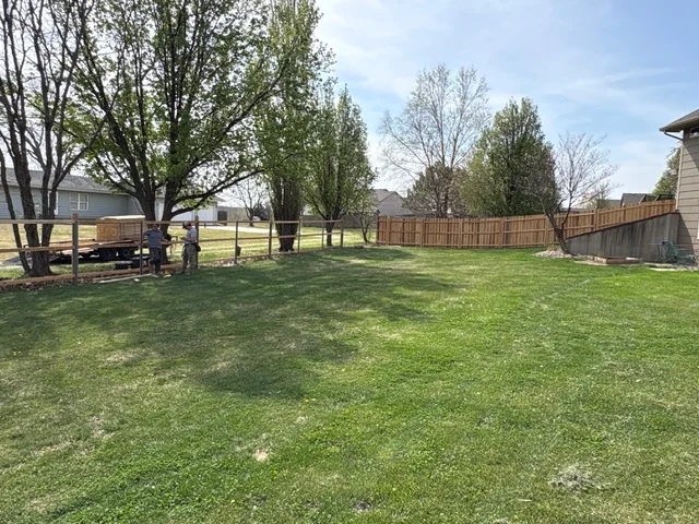 Wood privacy fence installation with stained boards along residential property
