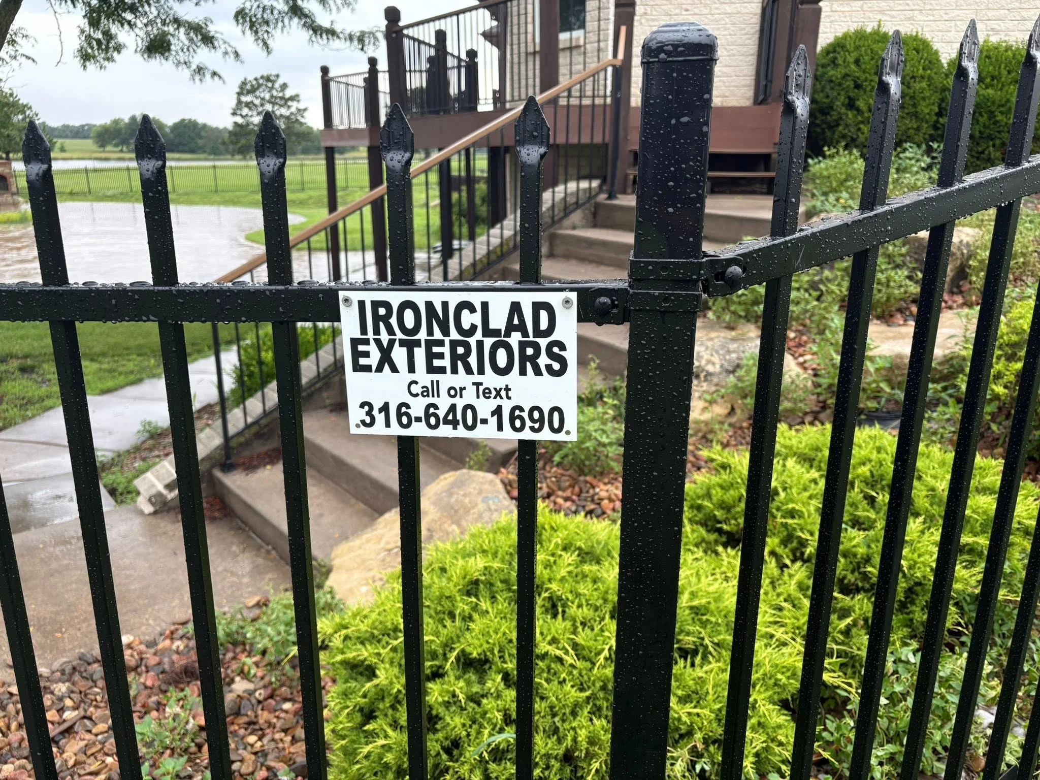 Black ornamental iron fence with spear-point pickets and horizontal rails installed at residential property