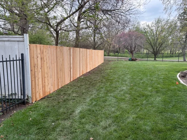 Newly installed cedar privacy fence with vertical boards along residential property line