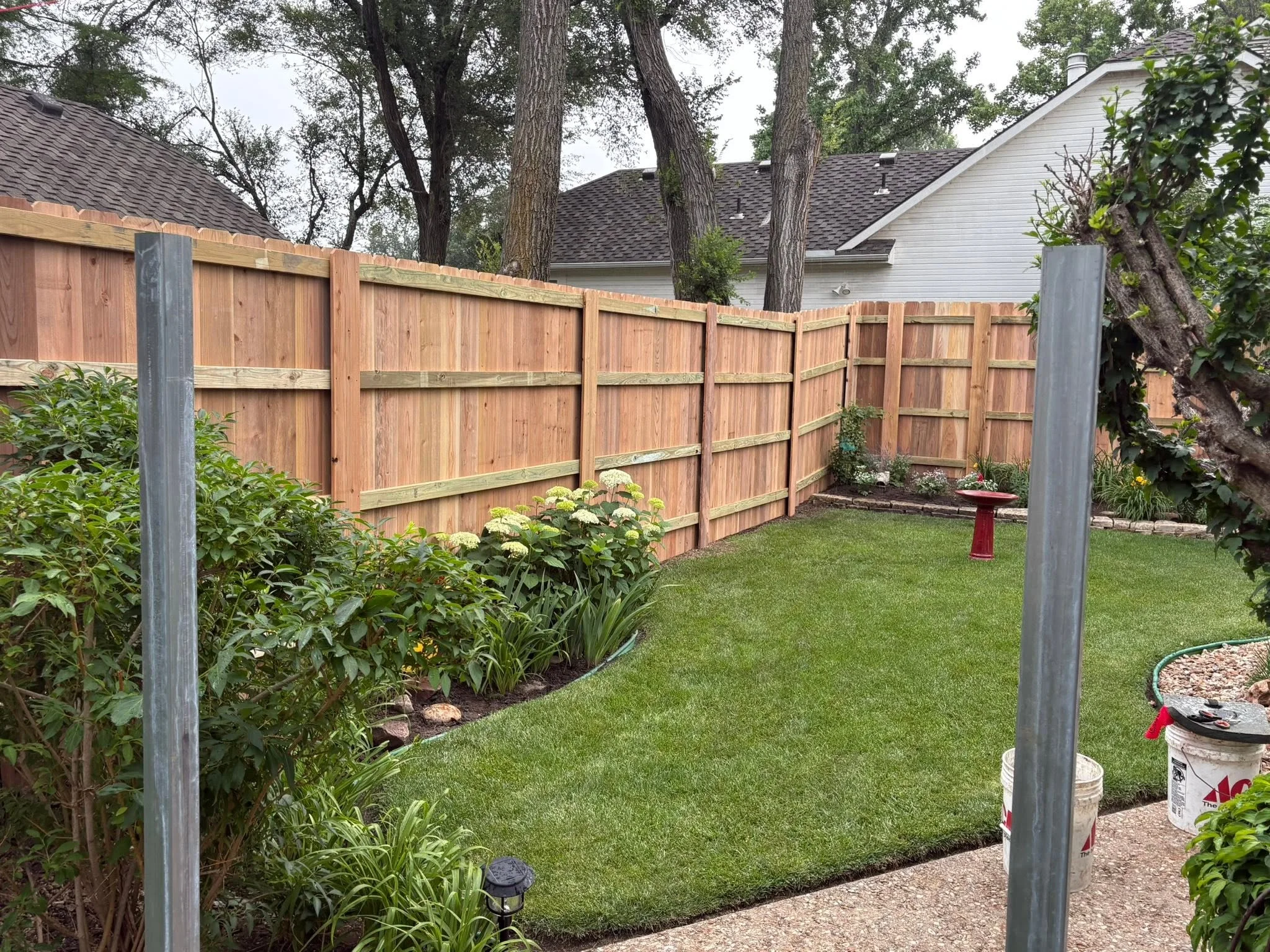 Cedar privacy fence with horizontal rails and concrete posts in residential backyard