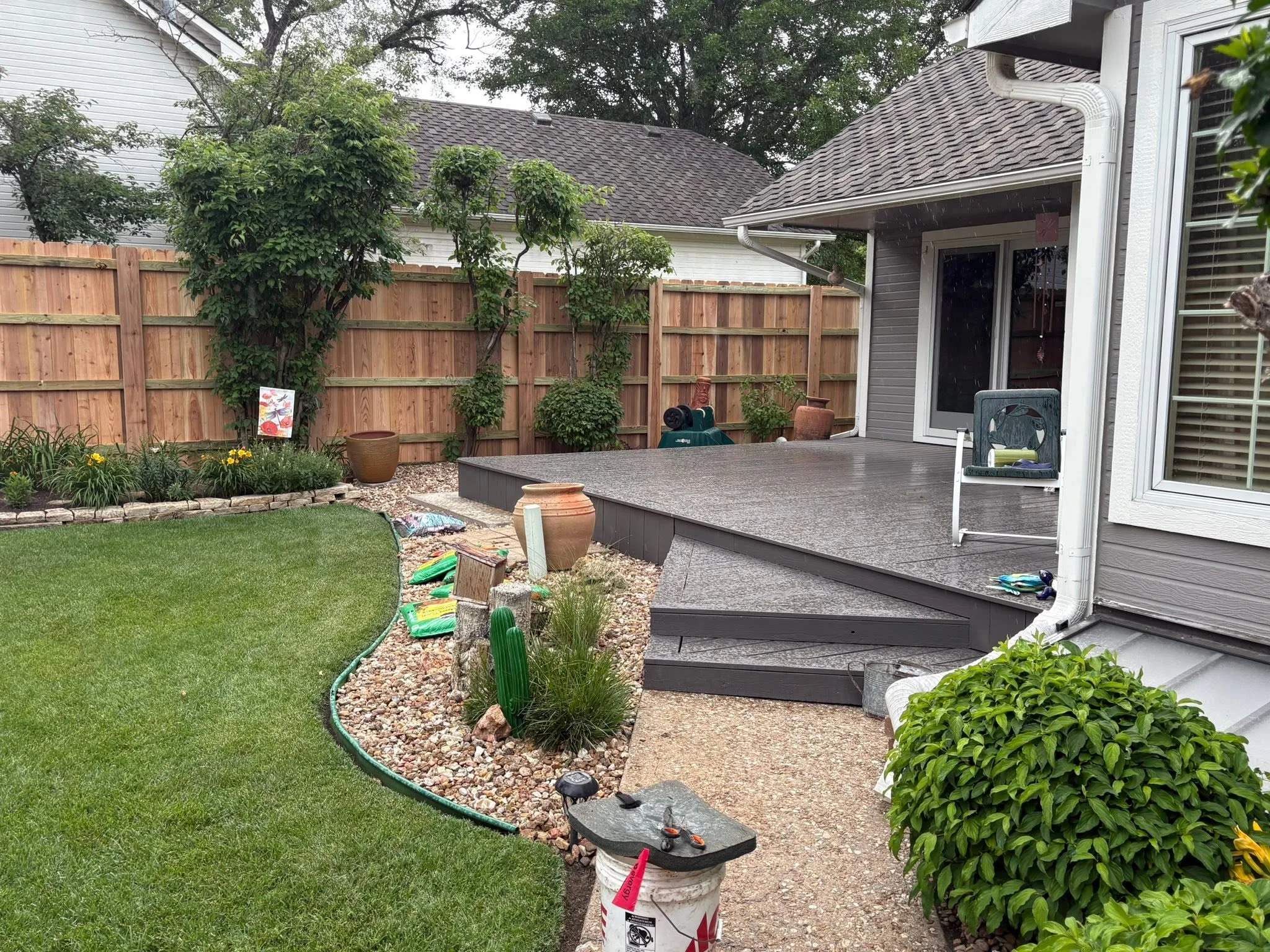 Cedar privacy fence with horizontal boards, stone edging, and integrated landscape plantings