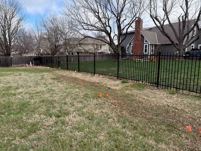 Black ornamental iron fence with vertical pickets installed along residential property