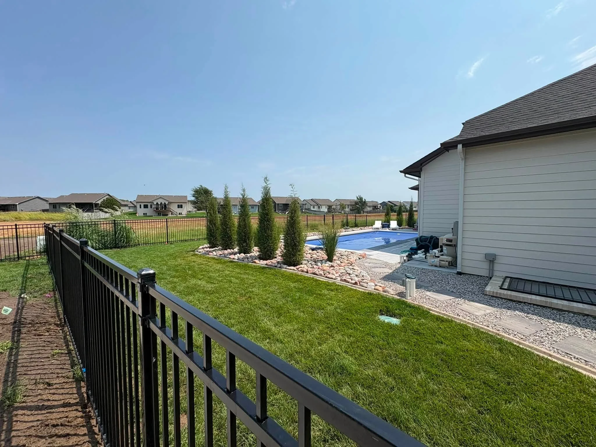 Black aluminum residential fence with vertical pickets installed along property line