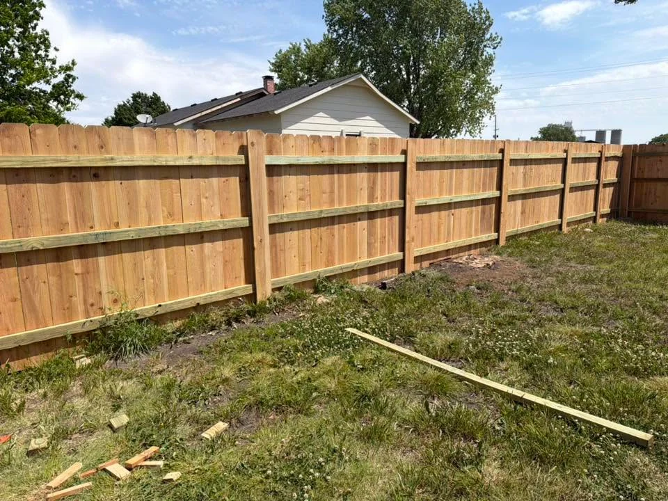 Cedar privacy fence with vertical boards and horizontal rails, newly installed in residential backyard