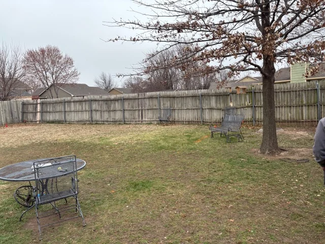 Wooden privacy fence with vertical boards installed around residential backyard perimeter