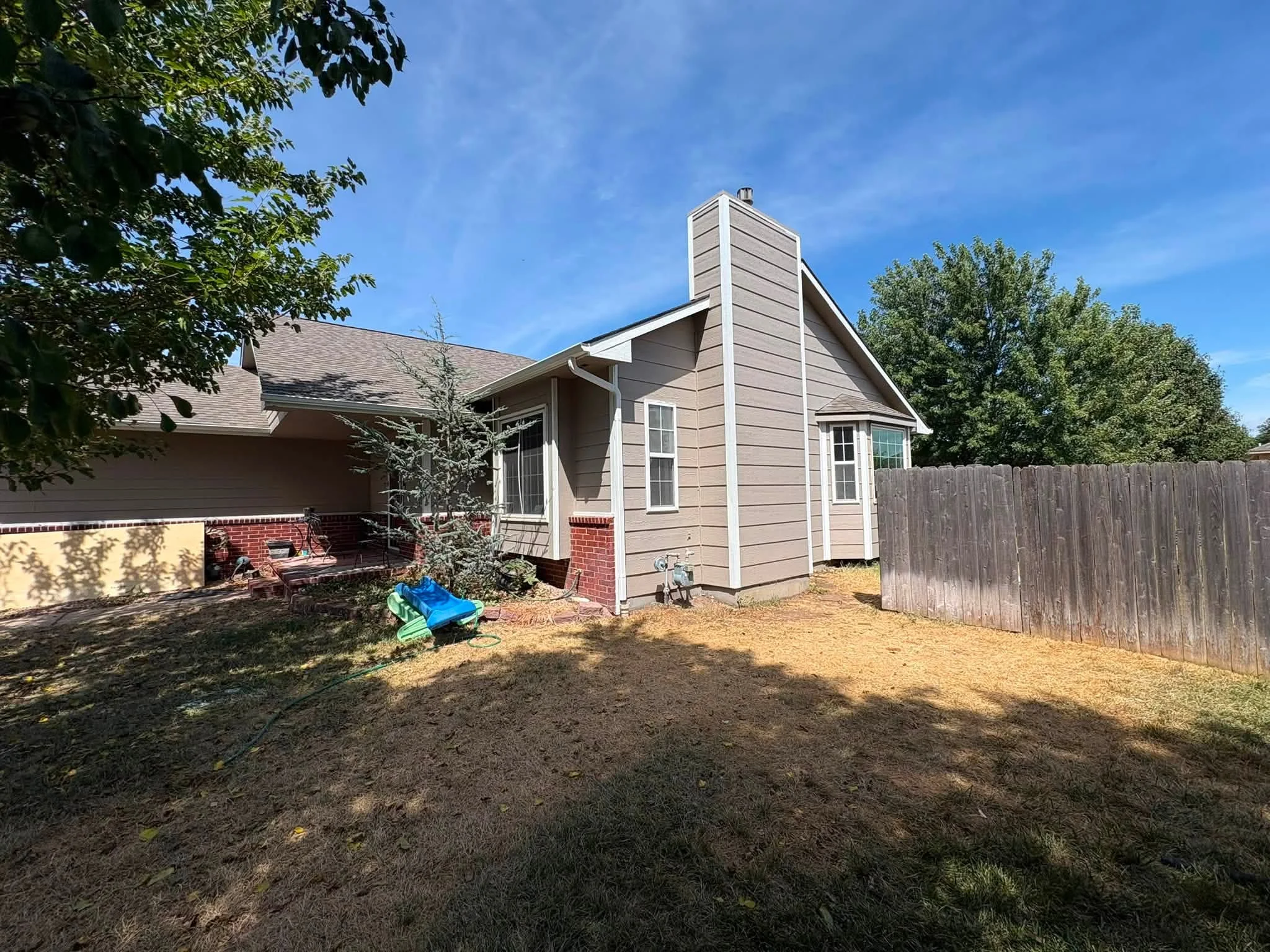 Weathered wood privacy fence installed along residential backyard perimeter with horizontal board construction