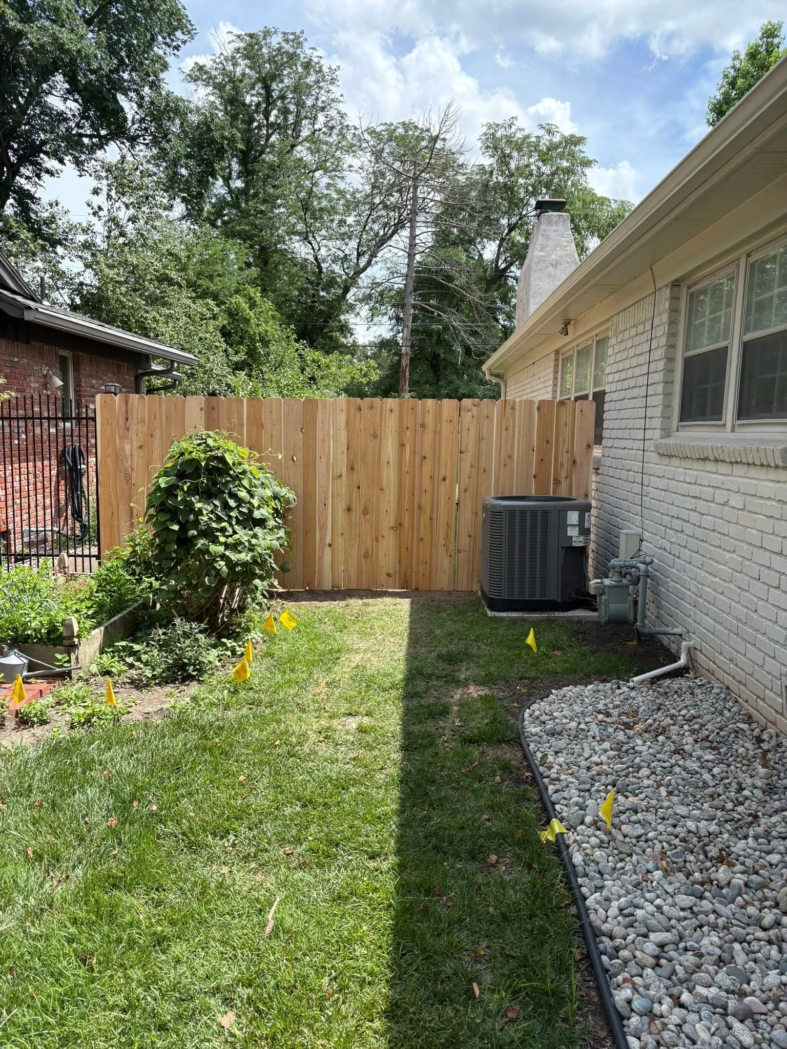 Cedar wood privacy fence with vertical boards installed along residential backyard property line