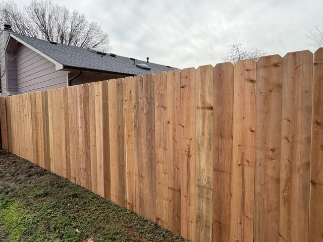 Cedar privacy fence with vertical boards, natural wood finish, residential installation