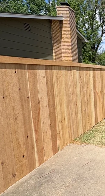 Cedar vertical board privacy fence with natural wood finish along residential driveway