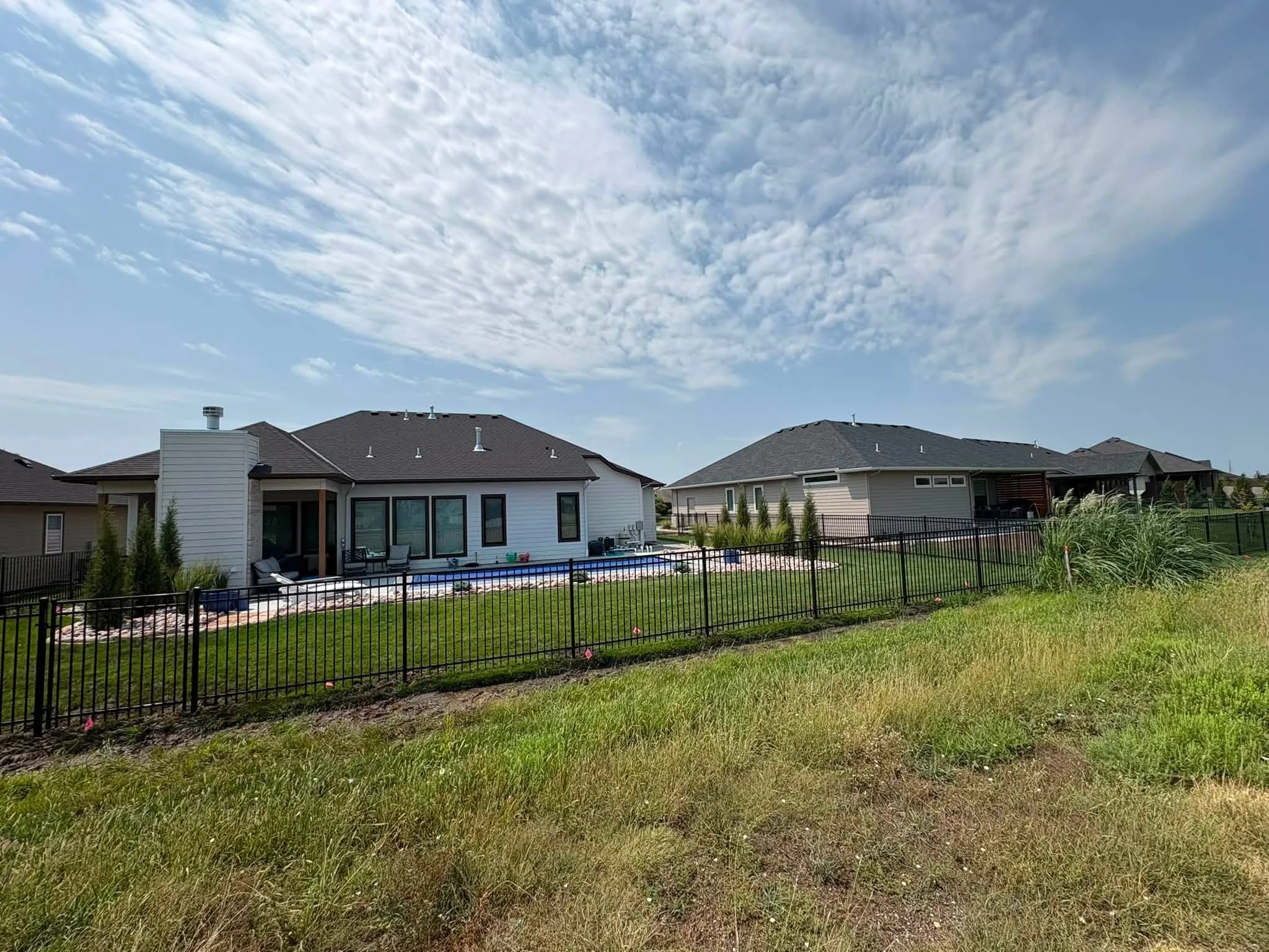 Black aluminum picket fence around residential pool area with manicured lawn