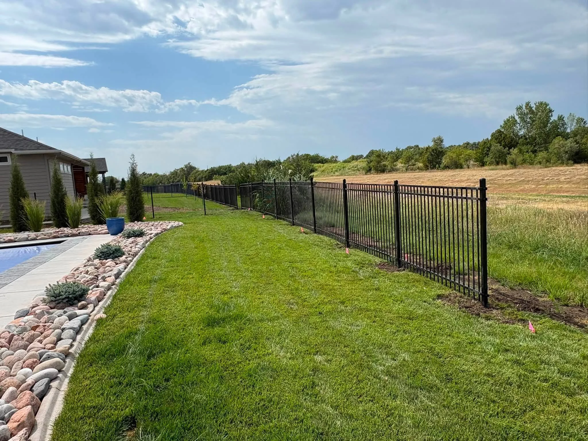 Black aluminum picket fence with vertical spindles installed along residential property line