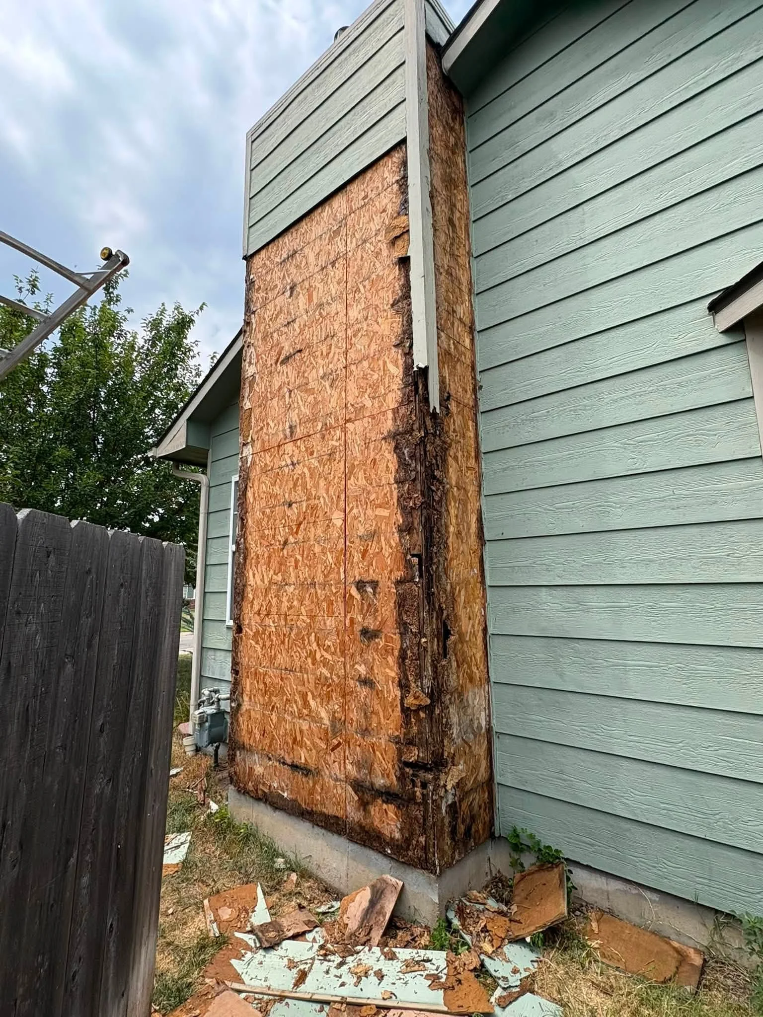 Damaged OSB sheathing and wood framing exposed on house exterior during siding replacement project