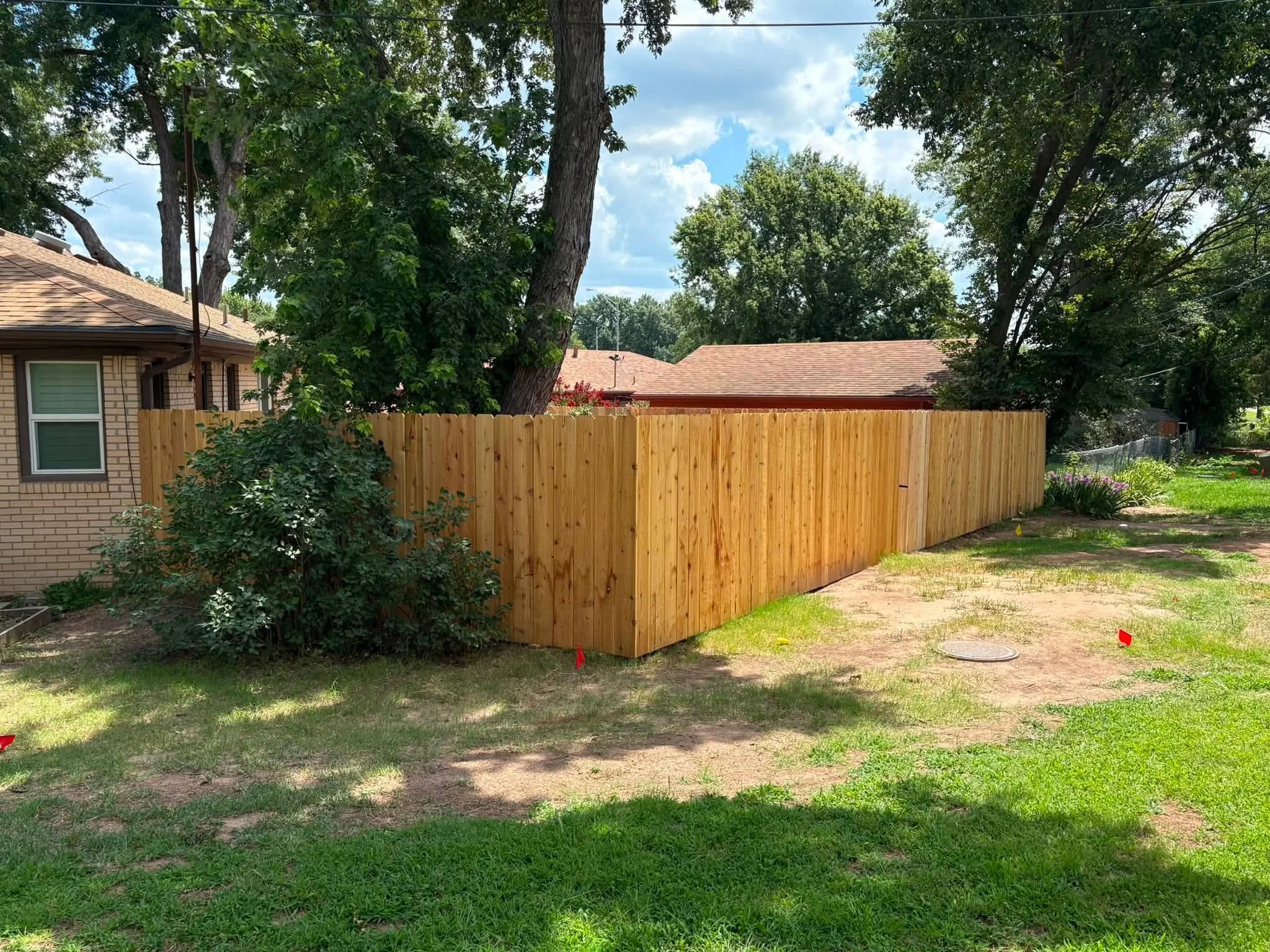 New cedar wood privacy fence with vertical boards installed around residential property