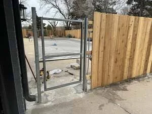 Wood privacy fence with vertical cedar boards and metal frame gate installation