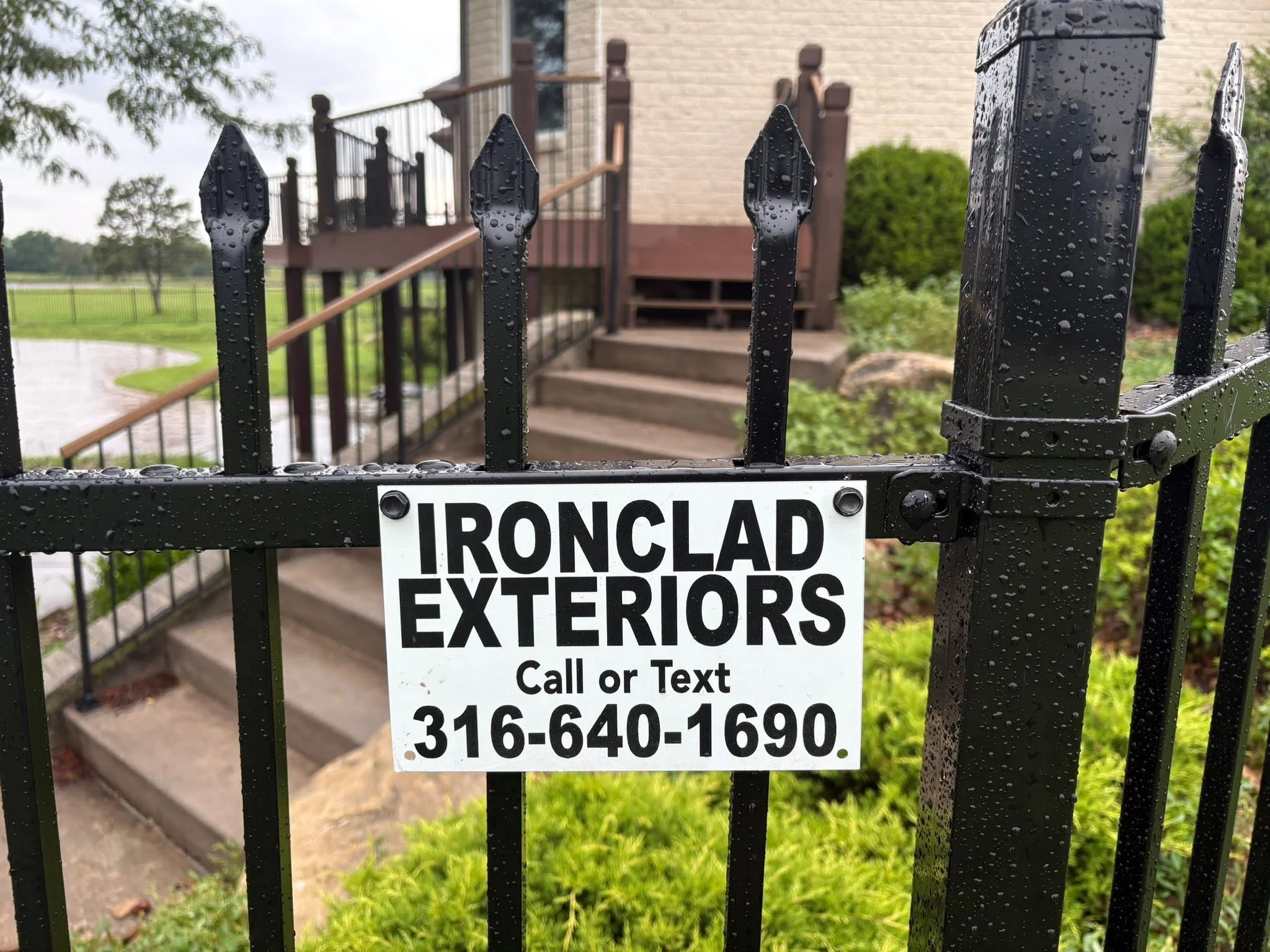 Black ornamental iron fence with spear-point pickets and horizontal rails installed at residential property