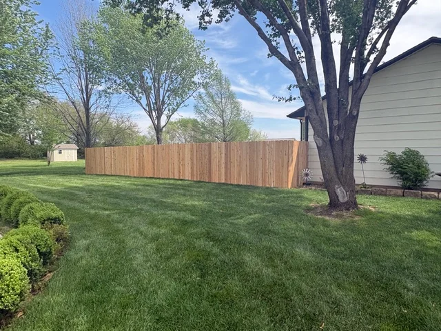 Newly installed wood privacy fence with vertical boards in residential backyard