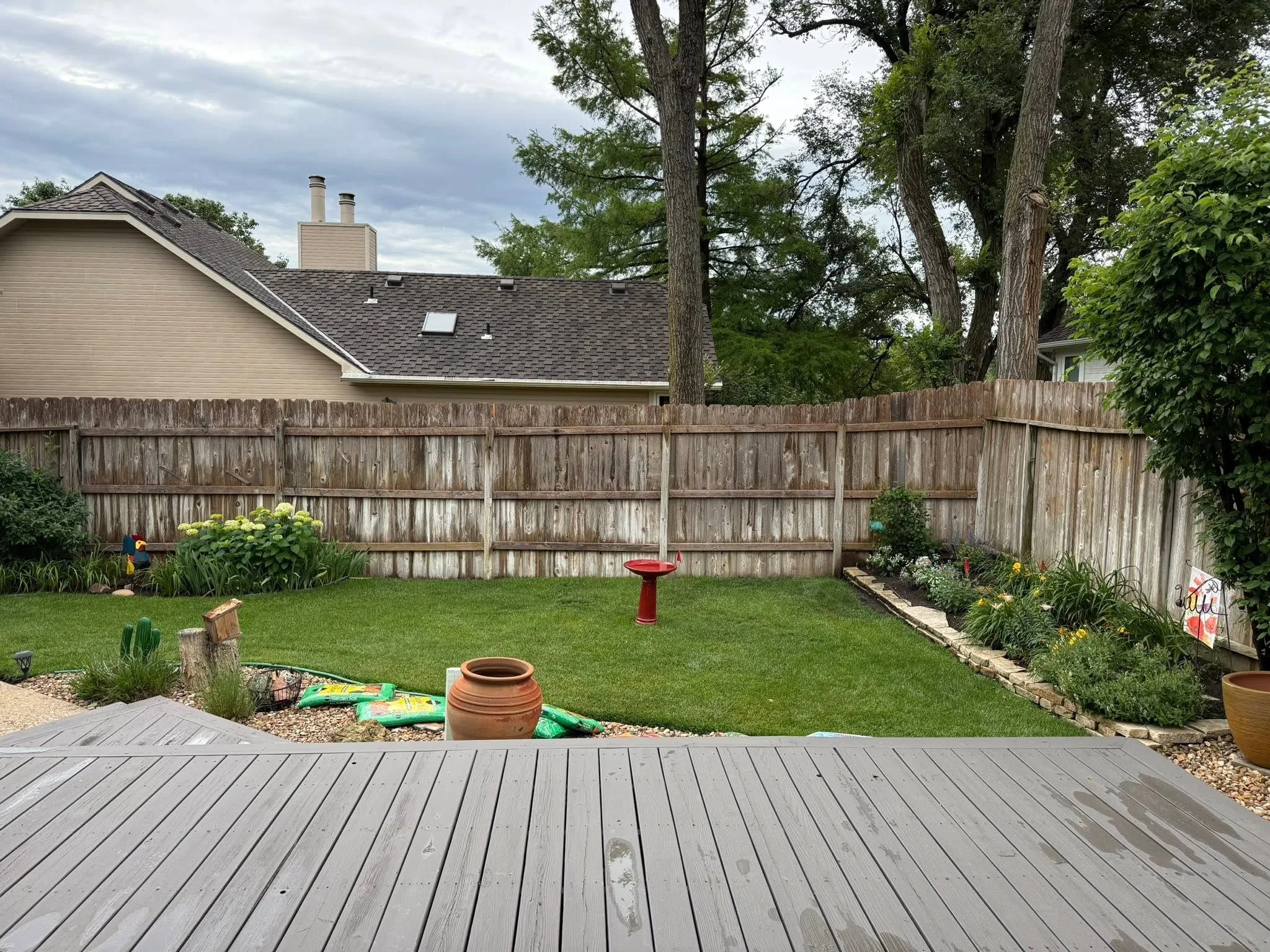 A repaired wooden privacy fence with straight posts and new boards in a residential backyard in Maize, Kansas. The replaced panels align cleanly with the existing fence line after storm damage repair.