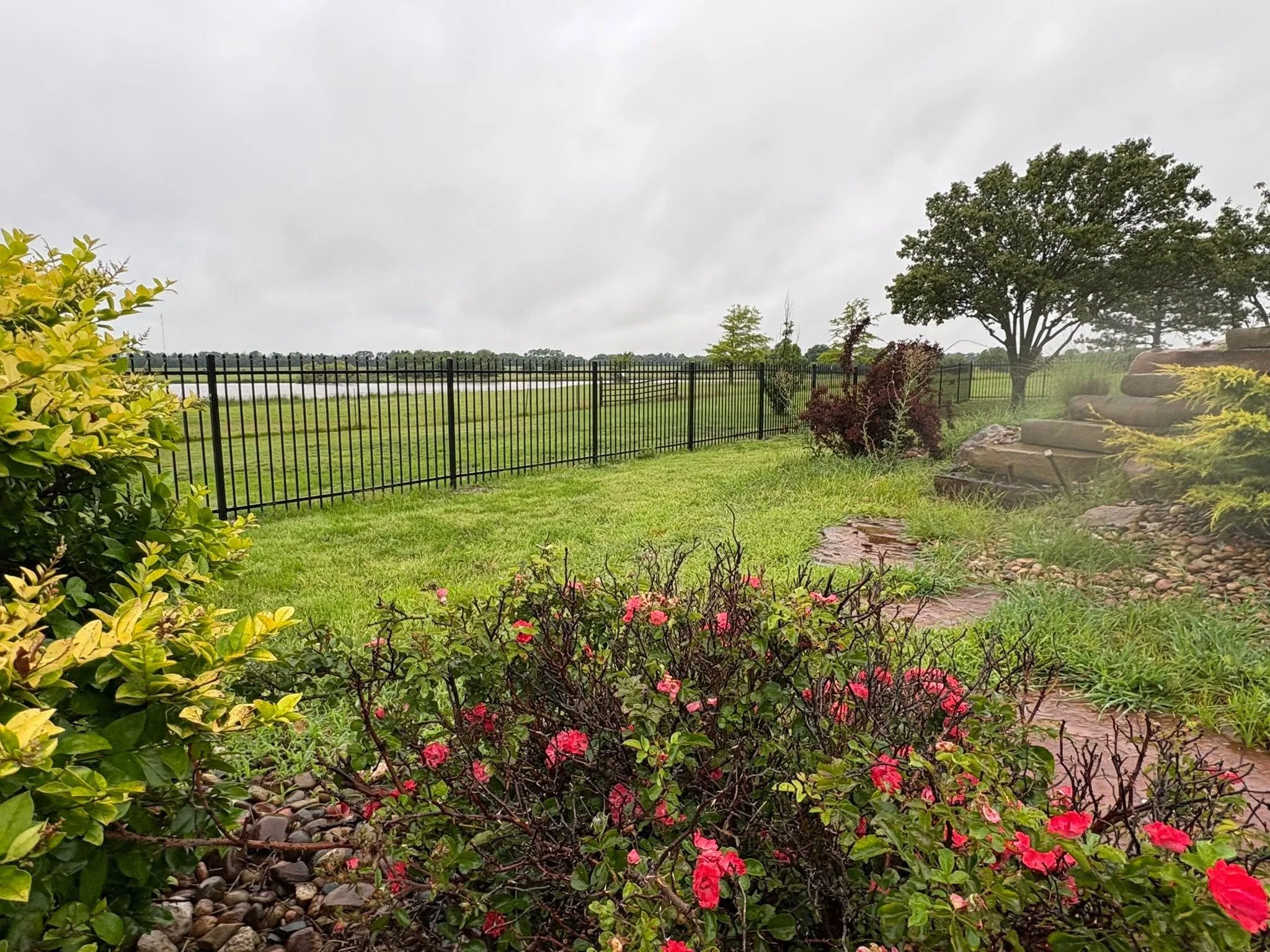 A freshly landscaped residential backyard in Maize, Kansas, with clean mulched garden beds, defined lawn edges, and level grading around a single-family home. Ironclad Exteriors landscaping work on a newly developed property in the Wichita metro area.
